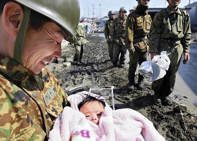 <p>Japonya'daki Tsunami sonrası enkazdan kurtarılan 4 aylık bebek bir Japon askerin kucağında. (2011)</p>
