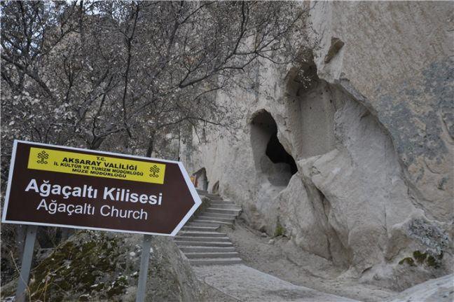 <p>Aksaray Ağaçaltı Kilisesi</p>

<p>Aksaray’ın hem doğal güzelliğini hem de tarihi mekanlarını bir arada sunan Ihlara Vadisi’nde bulunur Ağaçaltı Kilisesi.Vadinin giriş merdivenlerinde bulunan kilisenin gerçek girişi toprak altında olup, şimdiki girişi ikinci kat olarak bilinen kısımdadır. Kilisenin içinde bulunan resimlerin çoğu silinmiş olsa da hala görülmeye değerdir. Hristiyanlığa ait birçok tasvir görmek mümkündür.Ağaçaltı Kilisesi’nin yapılış tarihi kesin olarak bilinmiyor. Sadece IX.-XI. yüzyıllar arasında yapıldığı tahmin ediliyor. Harap olmasına rağmen hala ziyaret edilen kiliseyi Ihlara Vadisi gezinize dahil edebilirsiniz</p>
