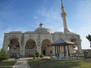 <p><strong>Muradiye Camii</strong></p>

<p>Edirne’nin dini yapılarından biridir Muradiye Camii. Mimar Sinan’ın ustalık eseri olarak nitelendirdiği Selimiye Camiigibi ziyaretçiler tarafında yoğun ilgi görür. Etkileyici bir hikayesi de vardır bu dini yapının. II. Murad’ın rüyasıyla başlayan bir hikaye…</p>

<p>Anlatılan efsaneye göre; II. Murat rüyasında Mevlana Celaleddin-i Rumi’yi caminin şimdiki bulunduğu noktada görür. Rüyasından çok etkilenen padişah, ferman çıkarır ve bu noktaya bir Mevlevihane yaptırır. Zaman geçtikçe de yapı, cami olarak kullanılmaya başlanır.</p>

<p>Muradiye Camii’nin mimarı hakkında bir bilgi bulunmamakla birlikte kitabesinin olmamasından dolayı yapılış tarihi de kesin olarak bilinmemektedir. Cami, kanatlı cami şeklinde inşa edilmiştir. Kesme taştan yapılmış olup, 3 kubbeye sahiptir.</p>

<p>Edirne’nin Merkez ilçesinde bulunan Muradiye Camii, sade ve muazzam mimarisiyle yüzyıllara meydan okuyarak günümüze kadar ulaşmayı başarmıştır. Merkezde bulunmasından dolayı, şehrin diğer gezilecek noktalarına oldukça yakındır. Edirne tatilinizde Muradiye Camii’ni ziyaret ettikten sonra; Ainos Antik Kenti’ni ve Üç Şerefeli Camii’ni gezmeyi unutmayın.</p>
