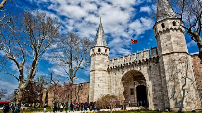 <p><strong>Topkapı Sarayı</strong></p>

<p>Kadıköy’den vapura binince hemen karşınızda tüm ihtişamı ile Eminönü’ye gidene kadar size eşlik eden  Topkapı Sarayı, İstanbul’un fethi sonrasında Fatih Sultan Mehmed’in İstanbul’a ve Osmanlı Devletine kattığı nadide eserlerdendir. Zamanla büyümüş ve gereksinimlere göre eklemeler de yapılmıştır.</p>

<p>1460-1478 yılları arasında yapılan Topkapı Sarayı, Padişahların, Sultanların evi, devletin yönetim ve eğitim merkezidir. Şehzadeler burada eğitilir, Devlet de buradan yönetilirdi.</p>

<p>Fatih Sultan Mehmed, “Yeni Saray” anlamına gelen Saray-ı Cedid adını vermişti bugünkü Topkapı Sarayına. Ancak, daha sonraları Sultan 1.Mahmud tarafından bizans surları yakınlarına yaptırılan ve önünde bulunan selam topları sebebiyle Topkapusu adındaki bu sahil sarayı bir yangınla tamamen kül olunca Saray-ı Cedid denilen Saray, Topkapı Sarayı adını almıştır.</p>

<p>Saray Planı, Fatih’in babası 2.Murad’ın Tunca Nehri kıyısında yaptırdığı bugün sadece kalıntıları bulunan, Edirne Sarayından ilham alındığı ve aynı ihtişam ve büyüklüğün Topkapı Sarayına örnek olmuştur.</p>

<p>Saray içerisinde Harem, Avlular, Bahçeler, Köşkler, Saray çalışanlarına ve Devlet idaresinde ayrılan bölümlerden oluşmuştur.</p>

<p>Bugün ziyaret etmek istediğinizde Topkapı Sarayında Harem ayrı bir bölüm ve ücrete tabi olmakla birlikte, 4 Avlu ve Bab-ı Hümayundan oluşur.</p>

<p>Bu bölümlerde Kutsal Emanetler, Padişah Silahları, Padişah Kıyafetleri, Saray Hazinesi, Mutfak Malzemeleri, Saraya hediye gelen yabancı devlet nişanları ve hediyeler ve Harem dairesi olarak sergilenmektedir.</p>

<p>Silahlar bölümünde, Fatih Sultan Mehmed, II. Bayezid, Yavuz Sultan Selim, Kanuni Sultan Süleyman, II. Selim, III. Mehmed, I. Ahmed gibi birçok Osmanlı Padişahına, sadrazam, paşa, silahtarağa gibi üst düzey devlet adamlarına ait silahlar sergilenmektedir.</p>

<p>Alemlerin efendisi Hz. Muhammed’in (s.a.v.) Hırka-i Saadeti, Sakal-ı Şerifi, Uhud savaşında kırılan dişinin muhafazası, Ayak izi, Ok ve Yayı  sergilenmektedir.</p>

<p>Bunlara ilave zamanla peyderpey Osmanlıya gönderilen kutsal emanetler içerisinde, Kabe duvarındaki Hacer-ül Esved taşının da muhafazası,  Hz. Musa’nın Asası, Hz. Davud’un kılıcı, Hz. Yusuf’un cübbesi, Hz. Fatmaya ait gömlek, hırka, seccade ve ashab-ı Kiram’a ait kılıçlar sergilenmektedir.</p>

<p>Saray Hazinesi bölümünün kuşkusuz ki yıldızı ve dünyaca ünlü mücevher 86 karat ve çevresinde 49 elmas ile süslü Kaşıkçı Elması’dır. Kaşıkçı elması ile birlikte sergilenenler arasında çeşitli diyarlardan gelen hediyeler, mücevherler, şehzade ve padişahların yaptırdığı Osmanlı İmparatorluğunun şanını ve büyüklüğünü simgeleyen birbirinden değerli Ok ve Yay torbaları, Nişanlar gibi birçok mücevher sergilenmektedir.</p>

<p>Saray’da gezerken dinlenebileceğiniz ve İstanbul’a ve Osmanlı’ya özgü hediyelikler alabileceğiniz mağaza ve cafe yer almaktadır.</p>
