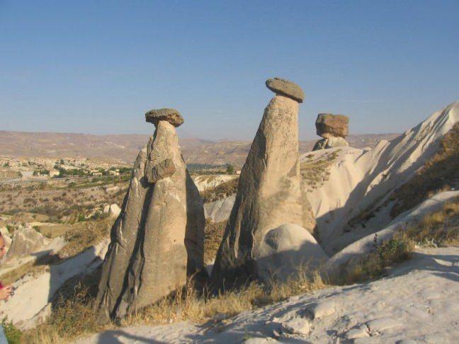 <p>Kapadokya Peri Bacaları</p>

<p>Kapadokya Peri Bacaları ile ünlenmiş doğal ve tarihi güzellikleri bünyesinde barındıran dünyaca ünlü bir tatil beldesidir.</p>

<p>Bu enteresan yapılar nasıl oluştu bu konuya değinirsek, Milyonlarca yıl önce Kapadokya bölgesi bir iç denizmiş. Yer kabuğu hareketleri ile çıkış yolu arayan magma, Erciyes Dağı, Hasan Dağı ve Güllüdağ yanardağlarından yeryüzüne çıkıp Kapadokya bölgesindeki denizi kurutmuş ve oluşan çukura lavlar dolmaya başlamıştır. Bu defalarca tekrarlamış yanardağlar aktifliğini yitirene kadar devam etmiştir.</p>

<p>Yanardağların ardından akarsular bu lav birikintileri arasında akarak derin vadileri oluşturmuşlardır. Rüzgarlarda bu oluşuma katılarak akarsuların oluşturduğu vadilerde dalga dalga görünüm oluşuyor. Rüzgarın etkisi bazı noktalardan ana parçadan kopmalara neden olmuştur.</p>

<p>Şapka görünümlü peri bacalarının şu anki şapka görüntüsünü almaları üst katmanı sert alt katmanı daha yumuşak olan bölgelerde rastlanır. Sert olan üst katman hacmi kadar alana baskı yapıp alt katmanıda sertleştiriyor. Sonuç olarak taşın altında kalan kısım rüzgara daha dirençli olup, bugünkü görüntüsüne kavuşuyor.</p>
