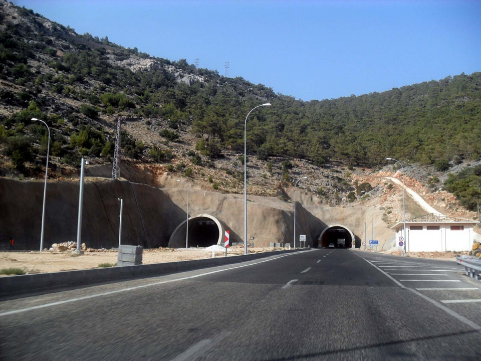 <p><strong>BOĞSAK TÜNELİ (2014)</strong><br />
<br />
Akdeniz Sahil Yolu Projesi ile<br />
Mersin - Antalya arasındaki mesafe 5 saate indi. Proje kapsamında, sahil yolu boyunca toplam 22 adet tünel bulunuyor.<br />
Uzunluğu 1570 m olan Boğsak Tüneli, çift tüplü olarak inşa edildi. 8 m platform genişliğine sahip tünel, toplam 65 milyon TL’ye mal oldu. 3,7 km’lik kısalma sağlanan yolda, seyahat süresi 30 dakika azaldı.</p>