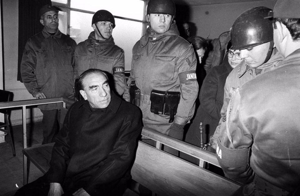 <p>Milliyetçi Hareket Partisi (MHP) Genel Başkanı Alparslan Türkeş (oturan) 30 Ekim 1978 tarihinde Almanya’nın Dortmund kentinde yaptığı salon toplantısında söylediği sözlerle hükümete hakaret ettiği gerekçesiyle Ankara 6. Ağır Ceza Mahkemesi’nde yargılandı. Türkeş’in eşi Seval Türkeş (gözlüklü)</p>