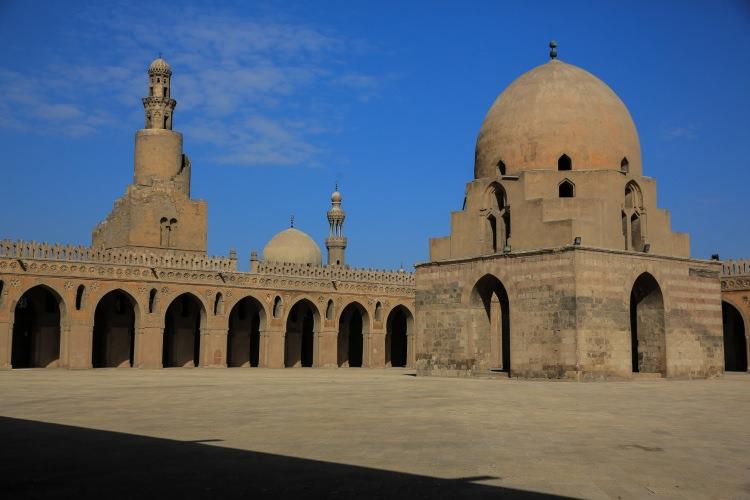 <p><strong>Caminin en önemli özelliklerinden biri minaresi</strong></p>

<p>Camiyi Mısır'daki diğer İslami yapılardan ayıran en önemli özelliği olan minaresi, 1296'da Memlük Sultanı Laçin'in talimatıyla yapılan onarım sırasında düzgün kesme taşla orijinal şekline yakın bir formda yenilenmiş.</p>

<p>Caminin kuzeybatı köşesinde yer alan minare orijinalde tuğla malzemeden ve spiral şekilde inşa edilmiş. </p>

<p>Sultan Laçin, orijinalinde çeşme bulunan avlunun ortasında kubbeli bir şadırvan yaptırmış. Onarımlarda yapıya silindirik formlu yüksek bir kasnak üzerine oturan kubbe de eklenmiş.</p>
