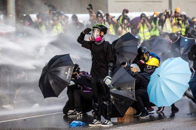 <p>Hong Kong'da süren protesto gösterileri sırasında tazyikli su sıkan polise tepki gösteren genç. </p>