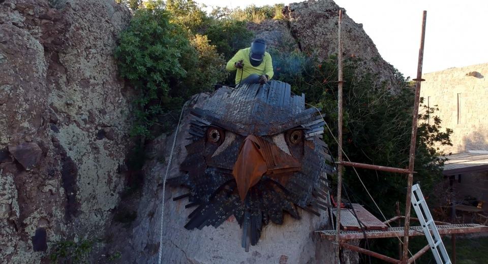 <p>Sanatçı, Bodrum'un Ortakent-Yahşi Mahallesi'ndeki lüks bir villanın bahçesinde bulunan yaklaşık 5 metrelik kaya parçası üzerine, hurdaya ayrılmış otomobil ve diğer metal parçalardan "kartal kafası heykeli" yaptı.</p>
