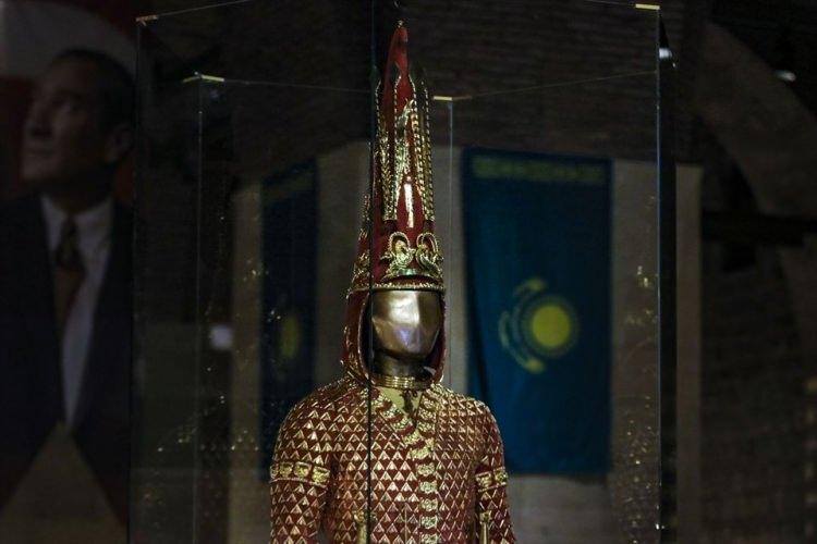 <p>Sağdan sola doğru kapanan V yakalı kısa kaftan, dar süvari pantolonu, diz altında kalan kısa yumuşak çizmeden oluşan zırh, 65 santimlik kalpağıyla dikkati çekiyor. Ucunda dağ keçisi motifi bulunan kalpakta, dünya hakimiyetini simgeleyen 4 okla güneş tanrısını sembolize eden 2 kanatlı at motifi dikkati çekiyor.<br />
</p>