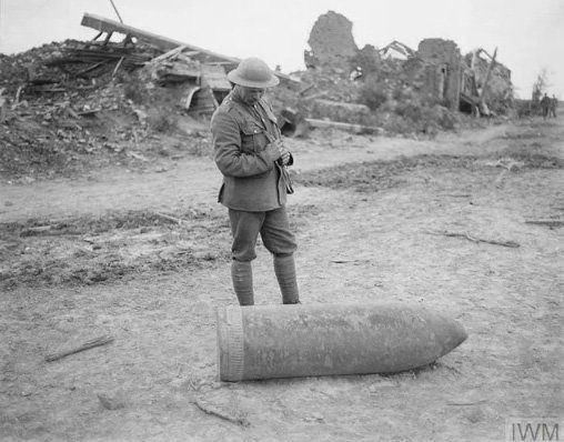 <p>Kullanıldığı halde patlamamış bir top mermisini kontrol eden bir İngiliz askeri, Belçika, 1917</p>
