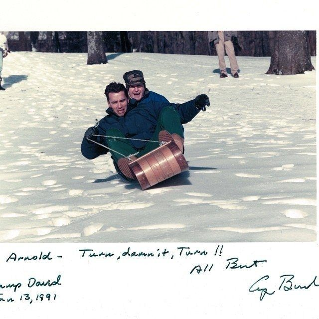 <p>Arnold Schwarzenegger ve arkasındaki Başkan George Bush, kızak kayarken, 1991</p>
