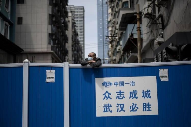 <p>&Ccedil;in'in Wuhan kentinde girişin yasak olduğu b&ouml;lgede barikatın &uuml;st&uuml;nden bakan bir maskeli adam</p>

