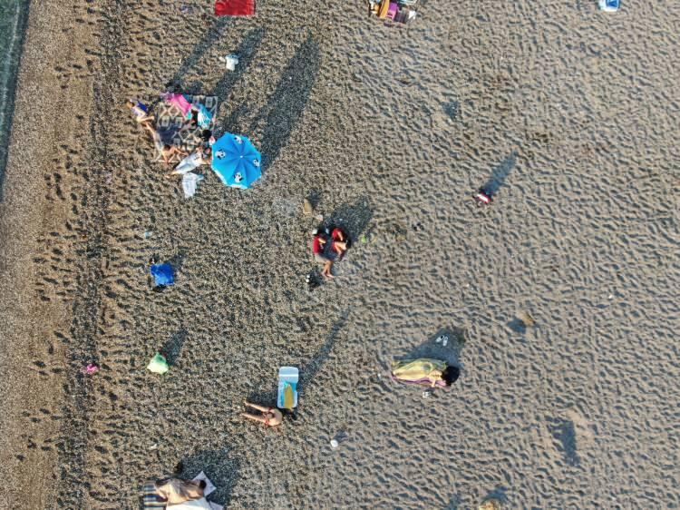 <p>Denize girmeyen kişilerin ise sahil bandında yürüyüş yapmayı tercih ettikleri görüldü.<br />
Sahilde uyuyanlar ve denize girenler havadan drone ile görüntülendi.</p>
