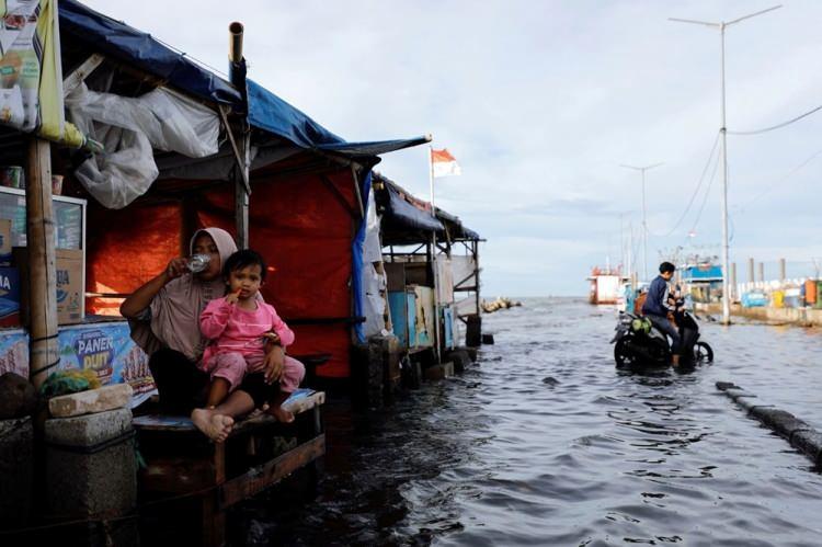 <p>9 Kasım'da 42 yaşındaki satıcı Zuriati, Endonezya'nın Jakarta kentinde, yüksek gelgitler nedeniyle sular altında kalan Muara Angke limanında müşterilerini beklerken, 3 yaşındaki kızı Syifa Belanursabila ile birlikte tezgahında oturuyor.</p> <p> </p> 