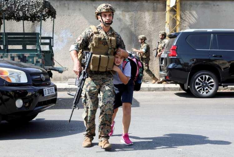 <p>Lübnan'ın Beyrut kentinde 14 Ekim 2021'de çıkan bir silah ateşinin ardından bir ordu askeri, bir kız öğrencinin ailesine ulaşmasına yardım ediyor.</p> <p> </p> 