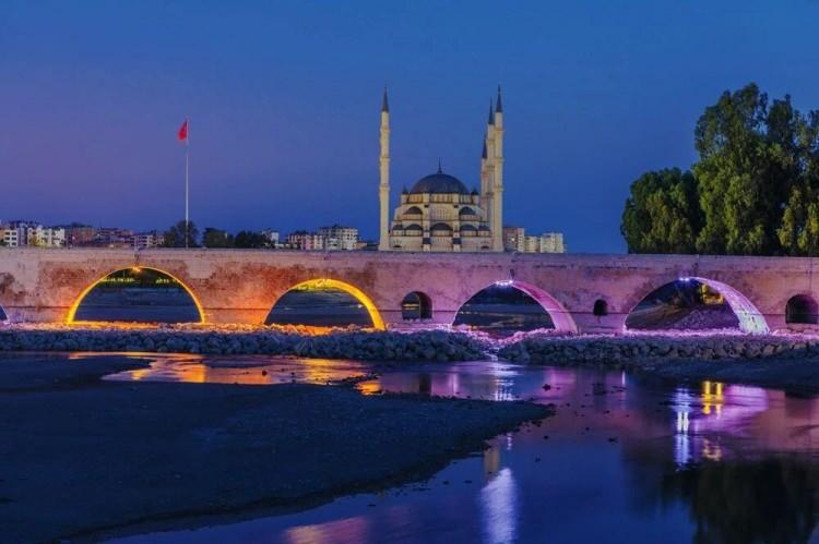 <p><strong>TAŞ KÖPRÜ</strong></p>
<p>Adana’nın Seyhan Nehri üzerinde yer alan Taş Köprü, dördüncü yüzyılda Roma İmparatoru Hadrianus tarafından yaptırıldı. Yüzyıllarca Avrupa ile Asya arasında önemli bir köprü oluşturan bu tarihi yapı 319 metre uzunluğunda ve 13 metre yüksekliğinde. Köprünün 21 kemerinden 14’ü hala ayakta. Ortadaki büyük kemerde iki aslan kabartması oldukça dikkat çekici. Taş köprü dünyanın kullanılan en eski köprüsü ünvanıyla da önemli bir yere sahip. Adana (Seyhan) ve Karşıyaka (Yüreğir) yakalarını birleştiren Taş Köprü Adana’nın en önemli simgelerinden. Bu göz alıcı köprüyü Adana’ya yolunuz düşerse mutlaka görmelisiniz.</p>