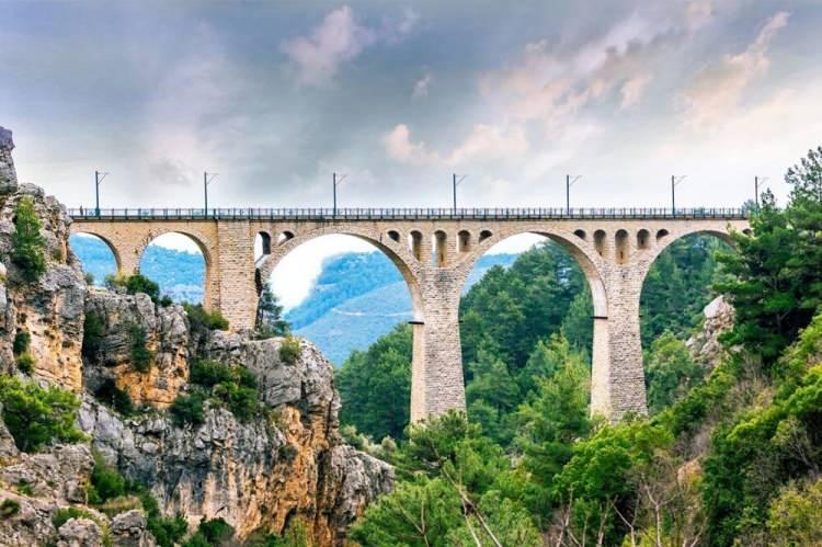 <p><strong>VARDA KÖPRÜSÜ</strong></p>
<p>Adana’nın Karaisalı ilçesinde yer alan Varda Köprüsü, halk arasında Koca Köprü olarak anılıyor. Osmanlı Hükümdarı 2. Abdülhamit ile Alman İmparatoru Kaiser Wilhem tarafından inşa edilen köprü 99 metre yüksekliğinde ve 172 metre uzunluğunda. Aynı zamanda vadiyi de birbirine bağlamakta. Hatta ”James Bond" serisinin "Skyfall" filminin aksiyon sahnelerinin de çekildiği Varda Köprüsü, çeşitli yerli ve yabancı filme ev sahipliği yapmasıyla da dikkatleri üzerine çekmekte. Alışılmışın dışındaki mimarı yapısı ve virajlı yoluyla özgün yapılar arasında yer alıyor. Ülkemizin tarihsel, kültürel ve doğal zenginlikleri açısından oldukça önemli bir yere sahip kentimiz Adana’ya giderseniz, Varda Köprüsü’nü mutlaka ziyaret etmelisiniz.</p>