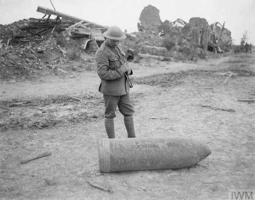 <p>Kullanıldığı halde patlamamış bir top mermisini kontrol eden bir İngiliz askeri, Belçika, 1917</p>
