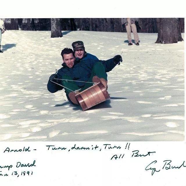 <p>Arnold Schwarzenegger ve arkasındaki Başkan George Bush, kızak kayarken, 1991</p>
