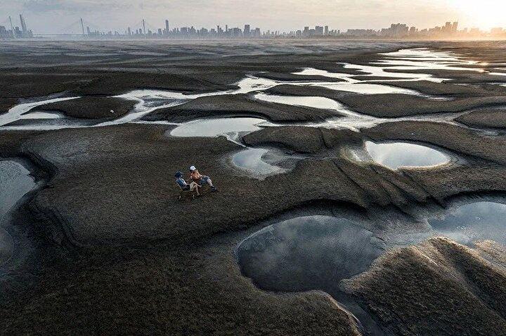<p>2 Eylül 2022'de çekilen bu fotoğraf, Çin'in orta Hubei eyaletindeki Wuhan'da Yangtze Nehri boyunca kavrulmuş bir nehir yatağının bir bölümünde oturan insanları gösteriyor.<br />
 </p>
