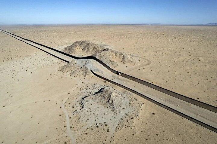 <p>19 Eylül 2022'de Meksika, San Luis Rio Colorado yakınlarındaki ABD - Meksika sınır duvarının bir bölümünün bulunduğu çöldeki bir tepenin havadan görünümü. Meksika ile ABD arasındaki duvar da vahşi yaşamı bozuyor: her iki ülkeden çevreciler tartışmalı yapı nedeniyle bölgeleri bölünen kedi, ayı veya geyik gibi farklı türlerin doğal yaşam alanlarını kurtarmak için uğraşıyor.<br />
 </p>
