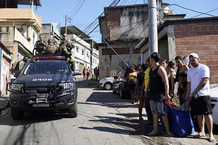 <p>21 Temmuz 2022'de Brezilya'nın Rio de Janeiro kentinde düzenlenen bir polis baskını sırasında ölü bir adamın cesedini taşıyan Complexo do Alemao favela sakinlerinin yanından bir polis kamyonu geçiyor. Polis ve yerel medyanın bildirdiğine göre, Rio de Janeiro'daki bir gecekondu mahallesinde düzenlenen organize suç operasyonunde en az 4 kişi polis tarafından öldürüldü.<br />
</p>