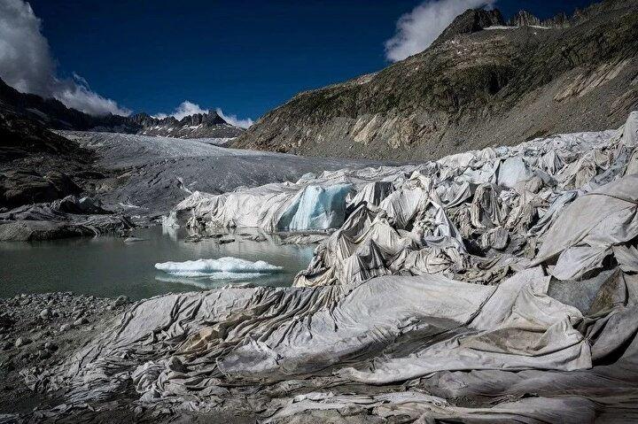 <p>8 Temmuz 2022'de İsviçre Alpleri'ndeki Gletsch yakınlarında çekilen bu fotoğraf, Rhone Buzulu'nun küresel ısınma nedeniyle erimesiyle oluşan buzul gölünün yanında erimesini önlemek için bir bölümünü kaplayan yalıtım köpüğünü gösteriyor. Rhone Buzulu, Fransız dijital görüntü çözümü girişimi Enlaps tarafından başlatılan ve küresel ısınmanın etkisinin belgelenmesine ve ölçülmesine yardımcı olan Planet Watch projesinin bir parçası olarak yüksek çözünürlüklü hızlandırılmış kameralarla izlenmek üzere dünya genelindeki on buzul arasından seçildi.<br />
</p>