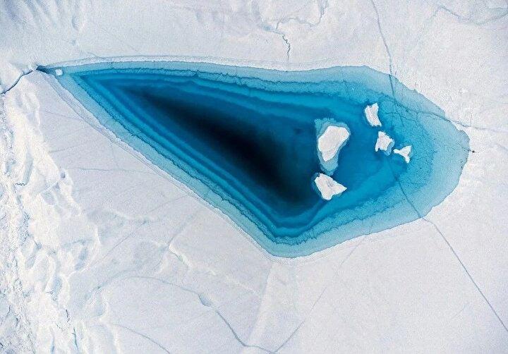 <p>29 Haziran 2022'de Batı Grönland, Ilulissat, Disko Körfezi'ndeki bir buzdağının tepesindeki büyük bir eriyik deliğinde turkuaz su görülüyor. Buzdağları, Kuzey Yarımküre'deki en verimli buzul olan Jakobshavn buzulundan (Sermeq Kujalleq) geliyor. Buzuldan kopan devasa buzdağları, okyanus akıntılarıyla güneye taşınmadan önce fiyordun önündeki sularda yıllarca yüzüyor.<br />
</p>