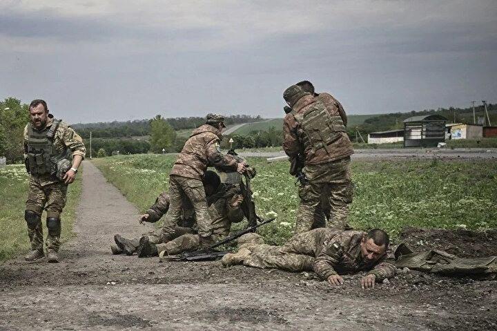 <p>Ukraynalı askerler, 21 Mayıs 2022'de Ukrayna'nın doğusundaki Donbas bölgesindeki cephe hattından çok da uzak olmayan silah arkadaşlarına yardım ediyor.<br />
 </p>
