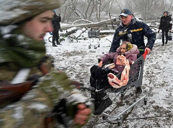 <p>8 Mart 2022'de Kiev'in kuzeybatısındaki Irpin şehrinin siviller tarafından tahliyesi sırasında bir görevli, içinde yaşlı bir kadın olan bir market sepetini itiyor. Savaşın ilk iki haftasında ülkede tam bir kaçış havası hakimdi.<br />
 </p>
