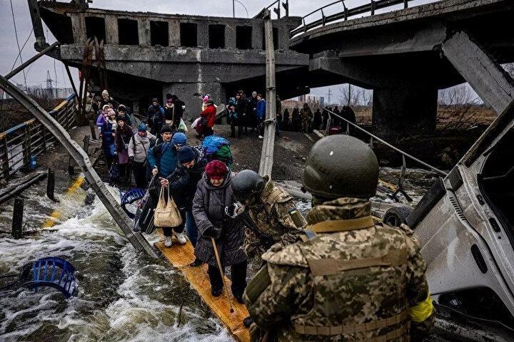 <p>Tahliye edilenler 7 Mart 2022'de Kiev'in kuzeybatısındaki Irpin şehrinden kaçarken yıkılmış bir köprüden geçiyorlar. Ukrayna, Moskova'nın bombalanan birkaç şehirden insani koridorlar kurma teklifini, bazı yolların mültecileri Rusya veya Beyaz Rusya'ya götüreceğinin ortaya çıkmasının ardından reddetti. Rusya'nın Kharkiv, Kiev, Mariupol ve Sumy'den güvenli geçiş önerisi, korkmuş Ukraynalı sivillerin önceki ateşkes girişimlerinde ateş altında kalmasından sonra gelmişti.<br />
 </p>
