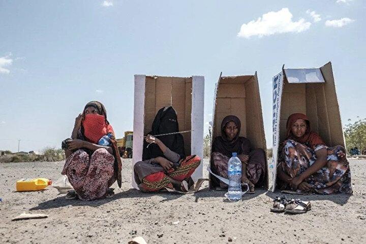 <p>Kadınlar, 14 Şubat 2022'de Etiyopya'nın Afar bölgesindeki Semera kentindeki Agda Oteli yerleşkesinde, Birleşmiş Milletler Mülteciler Yüksek Komiserliği (BMMYK) markalı karton kutuların altında oturuyor ve yetkililer tarafından kaydedilmeyi bekliyorlar. Semera'daki Ağda Otel yerleşkesi şiddetten kaçan yüzlerce sivili barındırıyor. İnsanların çoğu Barhale kampından yerinden edilmiş Eritreli mülteciler ama aynı zamanda yerinden edilmiş Etiyopyalılar da bölgede barınıyor. BM mülteci teşkilatından yapılan açıklamada hayatta kalanların, Tigray sınırına yakın Bahrale kampında 3 Şubat'ta başlayan şiddet olaylarında "en az beş mültecinin öldürüldüğünü ve çok sayıda kadının kaçırıldığını" bildirdi.<br />
 </p>
