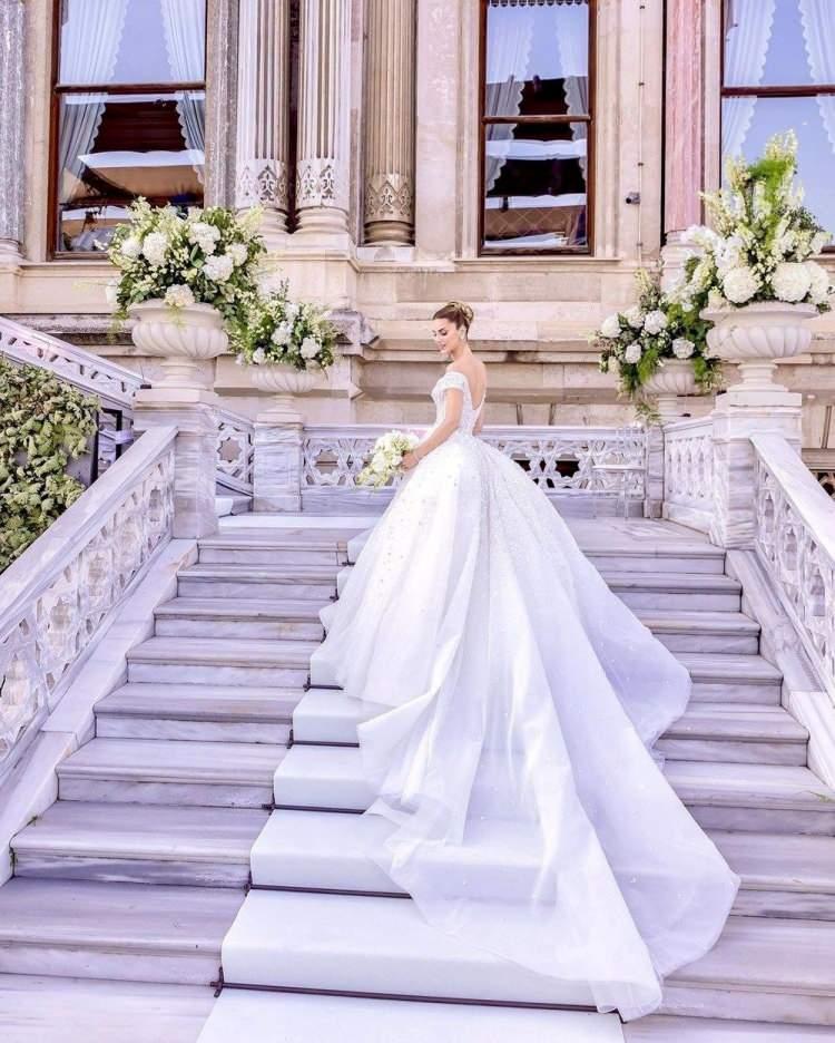 <p><span style="color:#000000"><strong>Zuhair Murad imzalı prenses model ve bol taşlı gelinlikle adeta bir peri kızına dönüşen Nazlı Kayı'nın gelinliği dört couture ustası tarafından titizlikle yapıldı.</strong></span></p>