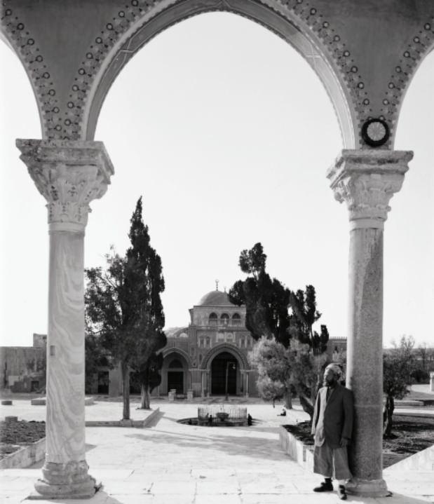 <p><span style="color:#FF0000"><strong>Aksa Camii: en g&uuml;zel ve en uzaktaki mescid</strong></span></p>

<p>Kur&rsquo;&acirc;n-ı Ker&icirc;m&rsquo;de kendisinden Mescid-i Aksa diye bahsedilen bu mescid Kud&uuml;s&rsquo;teki sosyal, ticar&icirc; ve hatta diplomatik hayatın merkezi konumundaydı. Arap&ccedil;a &lsquo;en g&uuml;zel&rsquo; veya &lsquo;en uzak&rsquo; anlamına gelen &lsquo;aksa&rsquo; ifadesi, Osmanlı tarihi boyunca bu uzak mescidi daha da g&uuml;zelleştirmek isteyen devlet adamlarının ilgisinde bulmuştur ifadesini. 1898-1914 tarihleri arasında &ccedil;ekilmiş olan bu fotoğrafta Kubbet&uuml;ssahra&rsquo;nın g&uuml;neyindeki merdiven başı kolonlarının s&uuml;slenmiş, Aksa Camii&rsquo;nin &ouml;n&uuml;ndeki K&acirc;se Şadırvanı&rsquo;nın etrafına demir parmaklıkların yerleştirilmiş olduğu g&ouml;r&uuml;lmektedir. Aksa K&uuml;lliyesi, 1898 yılında Kud&uuml;s&rsquo;&uuml; ziyaret eden Alman Kayzeri II. Wilhelm&rsquo;in ziyareti vesilesiyle esaslı bir tadilat ge&ccedil;irmiş, bu arada merdiven başı kolonlarının &uuml;zerindeki revaklar da sıvanmış ve geometrik fi g&uuml;rlerle s&uuml;slenmişti.&nbsp;</p>
