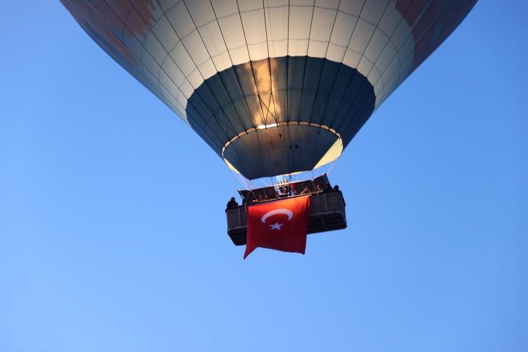 <p>Göreme beldesinde, gün doğmadan bayraklarla süslenen 150 sıcak hava balonu, 4 bin yolcu ile havalandı. Türk bayrakları ile göklere yükselen balonlar bir saat boyunca peribacalarıyla kaplı vadiler üzerinde uçuş gerçekleştirdi.</p>
