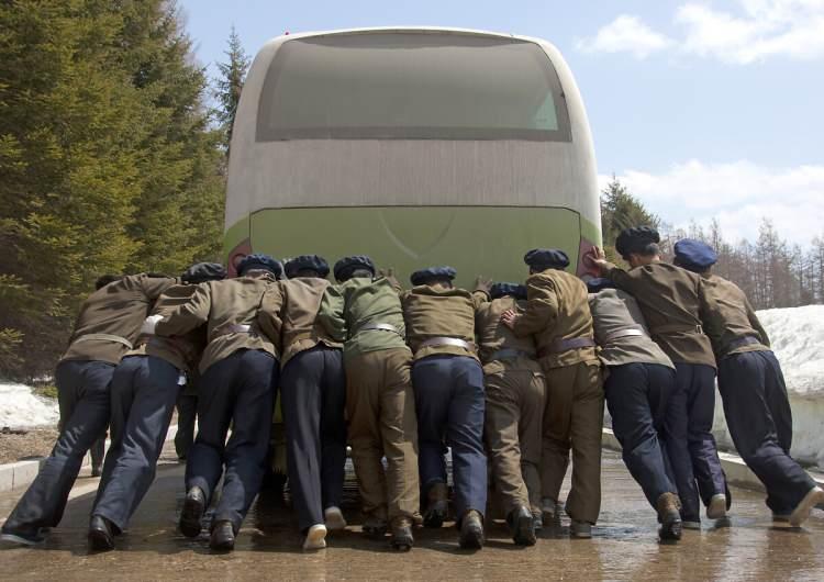 <p>Yolda kalmış bir otobüsü itenler.</p>