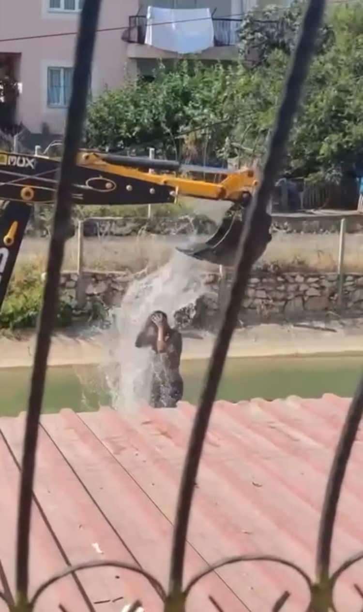 <p>Adana'nın Kozan ilçesinde bir iş makinesi operatörü sıcaktan bunalan vatandaşı kepçe ile serinletti. </p>