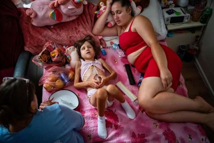 <p>Sonya Kryvolapchuk, 5, annesi Natalia, 27'nin yanında yarı baygın yatıyor ve Ukrayna'nın Chernivtsi kentindeki Misto Dobra Palyatif Bakım Merkezi'nde Retinoblastoma kanserinden vücuduna metastaz yapmış olan annesine bir porttan şırıngayla parasetamol veriyor, 28 Temmuz. Sonya'ya üç yıl önce beyin tümörü teşhisi kondu ve Rusya'nın Ukrayna'ya tam ölçekli işgalinin başlamasından üç gün sonra, 27 Şubat 2022'de Kiev'deki Ohmatdyt Hastanesi'nde kemoterapi görmesi planlandı. Rusya tam ölçekli işgaline başladığında, Sonya'nın ailesine hastanenin kaynaklarını yaralı askerleri tedavi etmeye yönlendirdiği ve Sonya'nın kemoterapisinin süresiz olarak erteleneceği söylendi. Natalia ve Sonya bunun yerine Polonya'ya yönlendirildi ve Sonya burada birçok test yaptırdı, ancak tedavi olmadı. Annesi tedavi için başka bir girişimde bulunmak üzere Ukrayna'ya dönmeye karar verdiğinde, kanseri tüm vücuduna yayılmıştı. Sonya Ağustos 2024'te vefat etti.</p>
<p> </p>
<p> <span style="color:rgb(163 165 169/var(--tw-text-opacity))">Lynsey Addario, The New York Times için</span></p>
<p> </p>