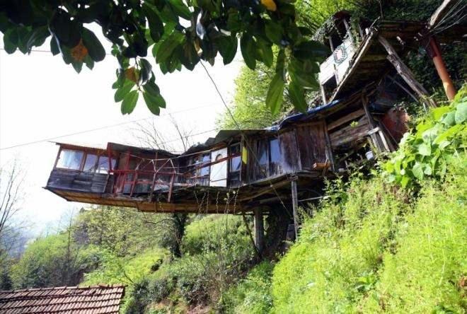 <p>Arazi yapısından kaynaklanan sorunlara vatandaşların farklı çözümler üretmesiyle dikkati çeken Rize, neredeyse her ilçesindeki ilginç evleriyle ziyaretçilerini şaşırtıyor.</p>
<p> </p>
<p>Güneysu ilçesine bağlı Gürgen köyünde yaşayan Bilal Atasoy da kayalara çelik halatlarla bağladığı evinde yaşamını sürdürüyor.</p>
<p>Yıllar önce arazisindeki yamaçta bulunan büyük kaya kütlesini oyan Atasoy, bu alana 6 metrekarelik tek odalı ahşap yapı inşa etti.</p>
<p>Atasoy, evini sağlamlaştırmak için çelik halatlarla çevredeki kayalara bağlayarak farklı bir yapıya imza attı.</p>