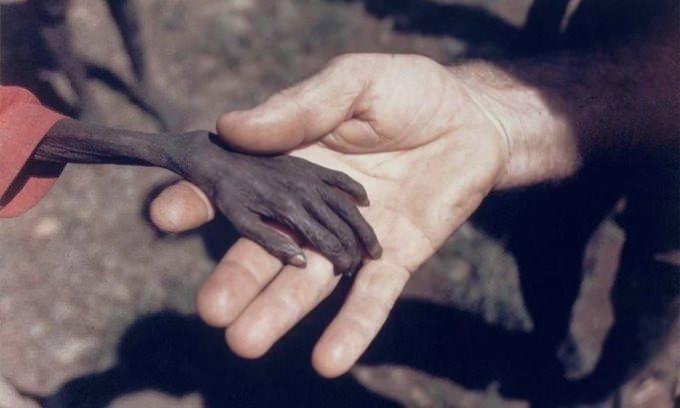 <p>1980 yılında fotoğrafçı Mike Wells, aç bir Ugandalı çocuğun elini tutan bir Katolik misyonerin bu fotoğrafını çekti.</p>
