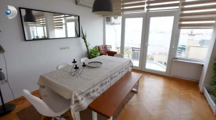 <p><strong>Geniş pencerelerin öne çıktığı oturma odası gri bir L koltuk, 6 kişilik yemek masası, büyük bir ayna ve kitaplıkla ferah bir atmosfere kucak açıyor.</strong></p>
