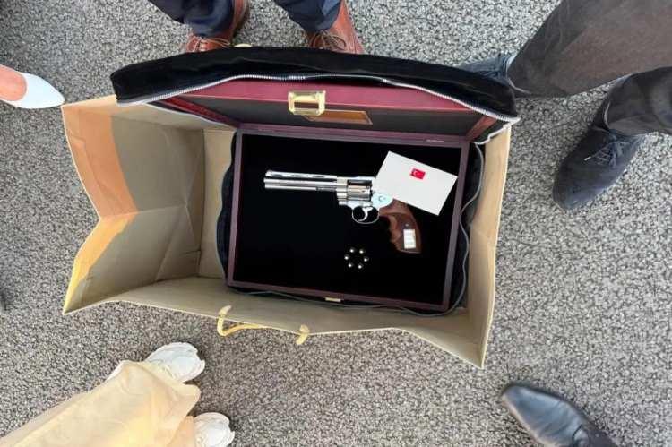 <p><span style="color:#B22222"><strong>G&Ouml;R&Uuml;NT&Uuml;S&Uuml; ORTAYA &Ccedil;IKTI</strong></span></p>

<p>Hediyeye ilişkin gelişmeler b&uuml;y&uuml;k yankı uyandırırken, &ouml;zel yapım revolverin g&ouml;r&uuml;nt&uuml;s&uuml; de ortaya &ccedil;ıktı.</p>

<p>&nbsp;</p>

<p>Gazeteci İbrahim Haskoloğlu tarafından paylaşılan fotoğrafta, kadife kaplamalı ahşap bir kutu i&ccedil;erisinde parlak metal g&ouml;vdeli revolver, yanında m&uuml;himmat ve T&uuml;rk bayraklı bir belge yer alıyor. Revolverin, liderlere &ouml;zel hazırlandığı belirtilen hediyelerden biri olduğu g&ouml;r&uuml;l&uuml;yor.</p>

