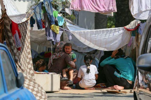 <p>Kıyafet ve çarşaflarla oluşturdukları tentelerin altında konaklayan ailelerden Muhammad Edib Khursan (sağda), "Kendimiz için değil, çocuklarımız için kaçıyoruz" dedi.</p>
