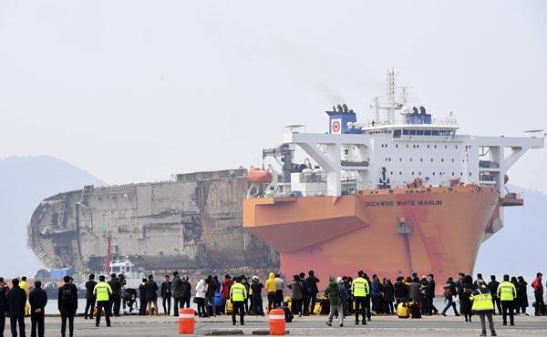 <p>Uluslararası ajansların bug&uuml;n ge&ccedil;tiği fotoğraflarda, 6 bin 325 ton ağırlığındaki dev feribotun Mokpo limanına getirildiği g&ouml;r&uuml;l&uuml;yor. Sewol gemisini deniz &uuml;zerine kurulan &ouml;zel sistem taşıdı, kıyıda &ccedil;ok sayıda insan karşıladı.</p>
