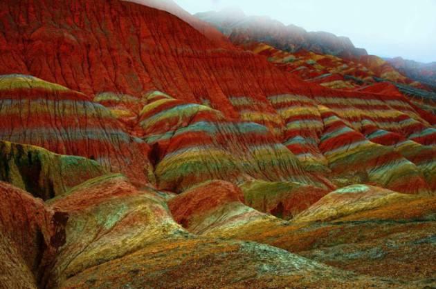 Usta bir ressamın ellerinden çıkmış yağlı boya tabloları andıran bu kareler aslında üzerinde ufak bir oynama bile olmayan fotoğraflar. Çin’in Gansu eyaletindeki Niciaying kasabasının Nantaizi köyünde bulunan bu tepelerin her şeyi doğal. Kırmızı kumtaşı katmanlarından oluşan bu arazi zaman içinde dik yamaçlar ve benzersiz kaya oluşumlarından meydana gelen dağlık bir araziye dönüşmüş. Bu tarz bir kaya oluşumu sadece Çin’de bulunuyor.