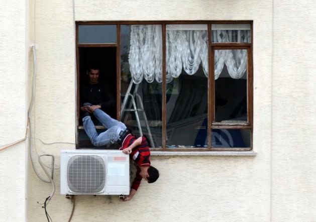 Yaklaşık 15 dakika s&uuml;reyle arkadaşının yardımı ile v&uuml;cudu tamamen sarkık bir şekilde 4. kat penceresinde &ccedil;alışan klima ustası, caddeden ge&ccedil;en vatandaşların ilgi odağı oldu. 