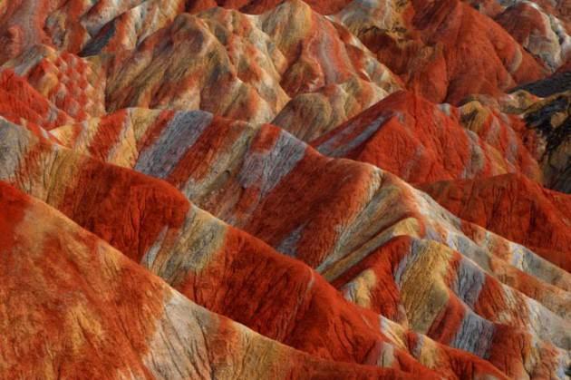 Usta bir ressamın ellerinden çıkmış yağlı boya tabloları andıran bu kareler aslında üzerinde ufak bir oynama bile olmayan fotoğraflar. Çin’in Gansu eyaletindeki Niciaying kasabasının Nantaizi köyünde bulunan bu tepelerin her şeyi doğal. Kırmızı kumtaşı katmanlarından oluşan bu arazi zaman içinde dik yamaçlar ve benzersiz kaya oluşumlarından meydana gelen dağlık bir araziye dönüşmüş. Bu tarz bir kaya oluşumu sadece Çin’de bulunuyor.