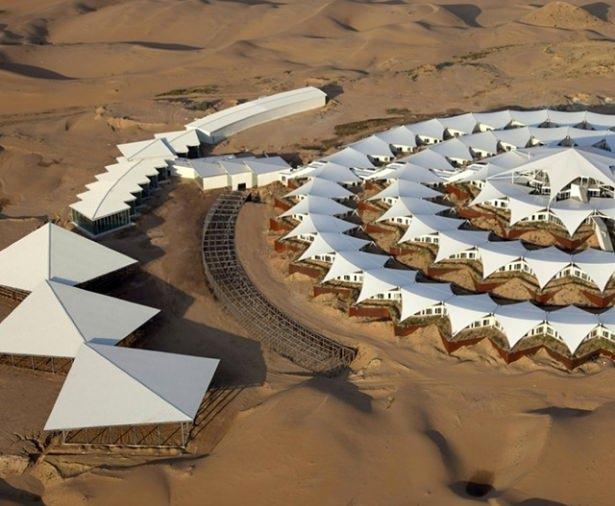 <p>Desert Lotus Hotel", yapı olarak üçgen beyaz çadır ile üstleri kapatılmış bir tasarıma sahip ve bir lotus gibi 45 derece döndürülmüş dairesel oluşum ile birbirine bağlı.</p>
