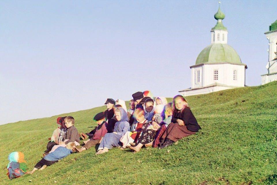<p>Rusya’da 1909’da çekilen fotoğrafta, Rus çocuklar bir kilise ve çan kulesi önünde oturuyor</p>
