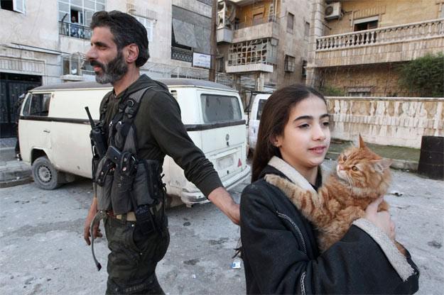 Reuters muhabiri Muzaffer Salman'ın &ccedil;ektiği fotoğraflardan ilkinde, &Ouml;zg&uuml;r Suriye Ordusu'na mensup bir silahlı muhalif, kucağındaki kedisiyle &ccedil;atışmaları izleyen kızına kenarda durmasını tembihlerken g&ouml;r&uuml;l&uuml;yor.