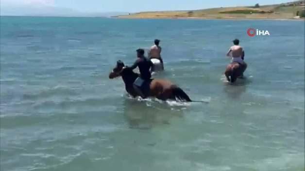 Muradiye ilçesinde sıcak havadan bunalan gençler, atlarıyla birlikte Van Gölü'nde yüzerek serinliyor.