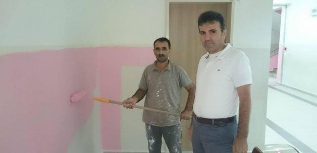 Okul müdürü, işçilerle okul binasının boyanmasında çalışıyor